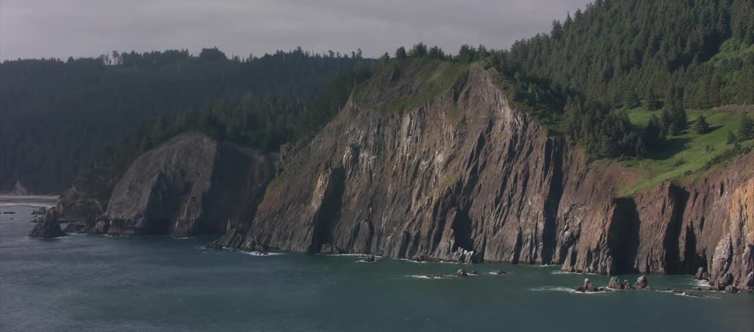 A large cliff looms over deep blue ocean