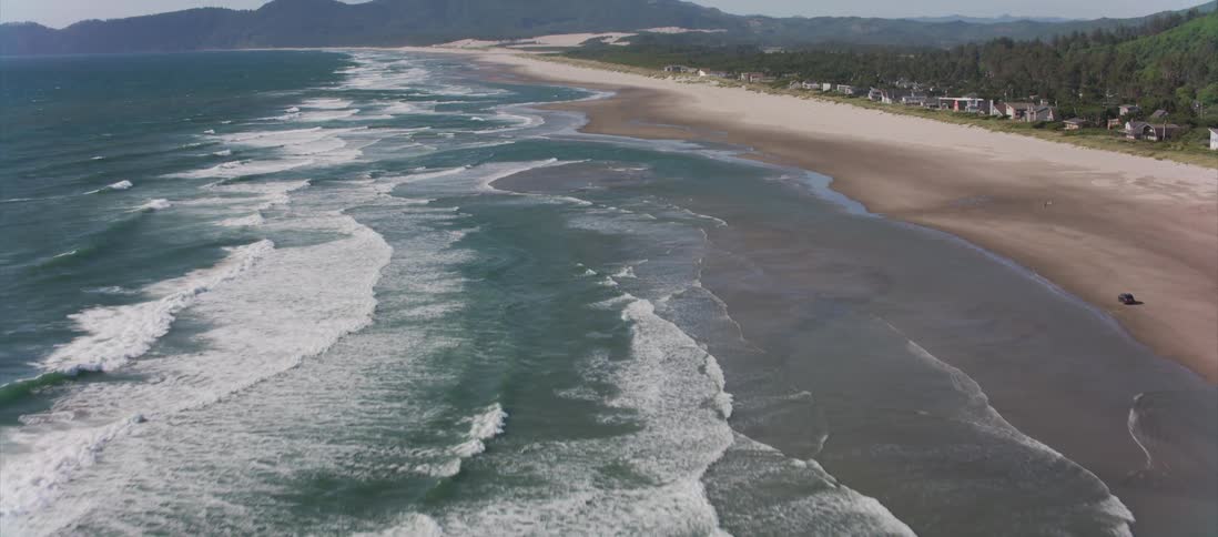 Camera flies along the ocean coast covered with sand