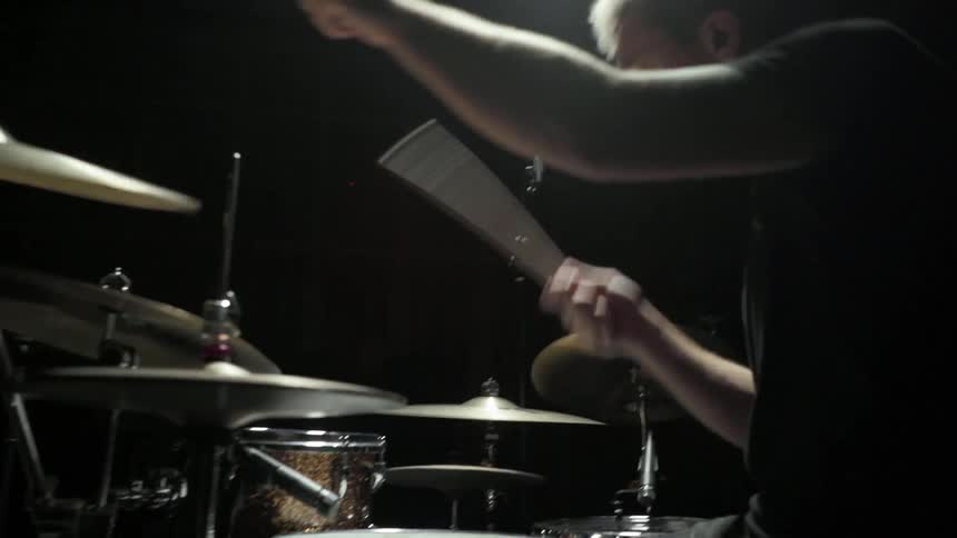 A man slamming drumsticks onto a set of drums