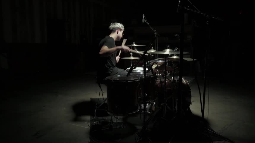 A man playing the drums in a dark room