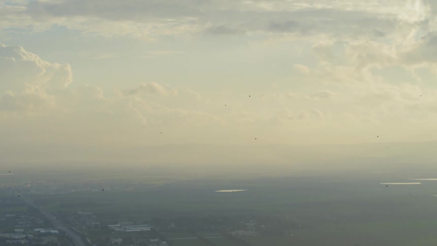 Skyline of the foggy sky with clouds while birds fly up in the air in the daytime