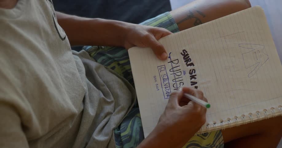 A man sitting on a couch writing on a notebook