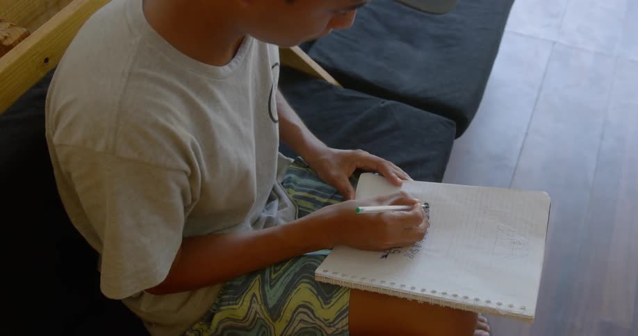 A man indoors writing on a notebook