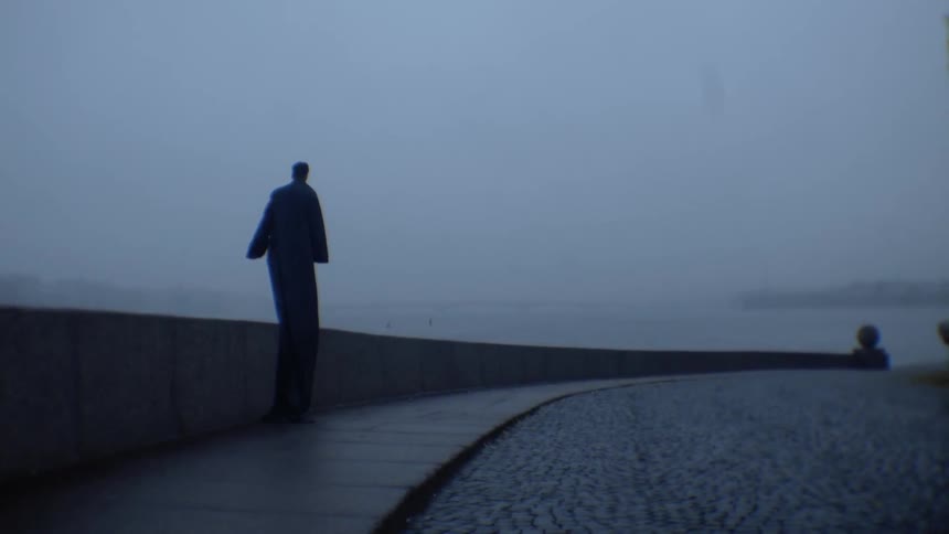 A person with a long cloak walking on a wall
