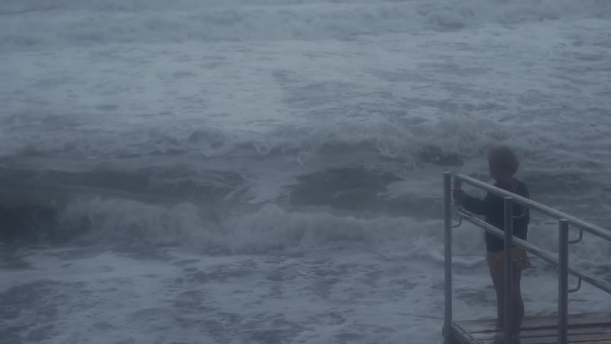 Woman standing next to waves