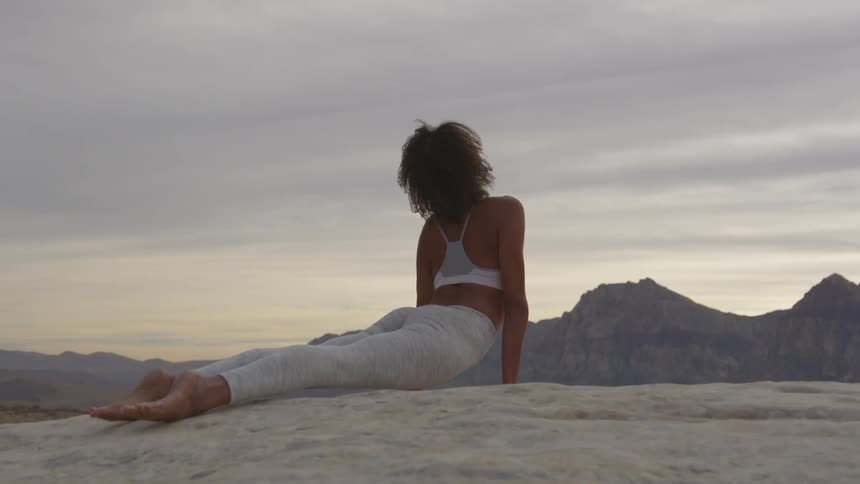 A young woman does yoga on a mountain top
