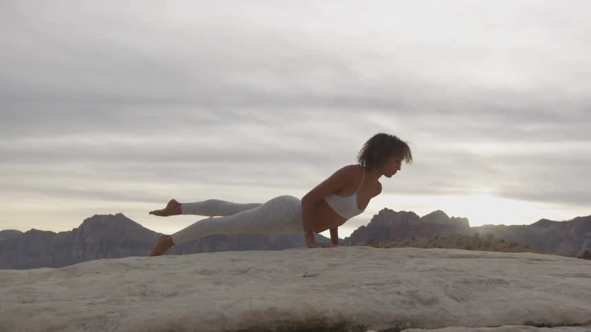 A woman does yoga on a mountain top