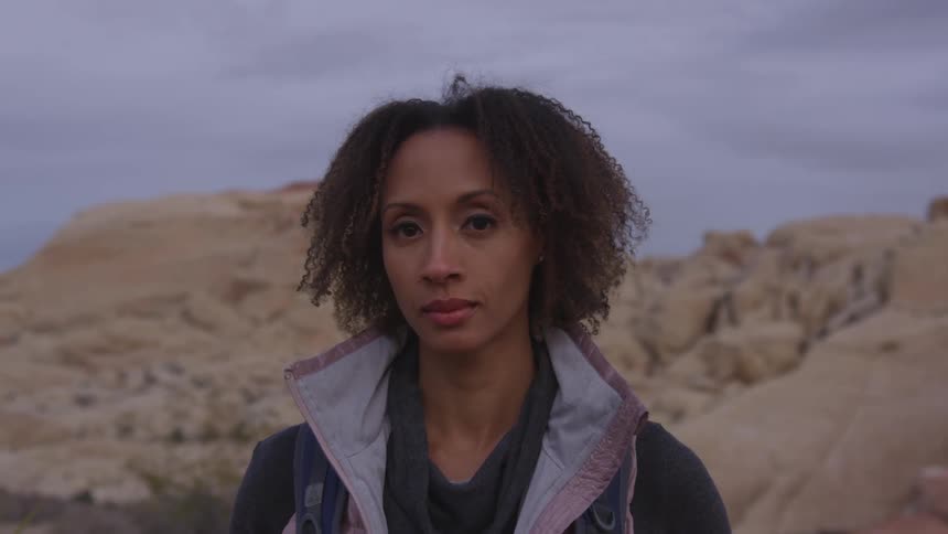 Woman looking at the camera while standing on a desert