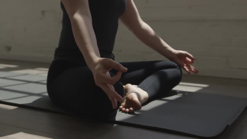 A woman sitting on a mat inside meditating