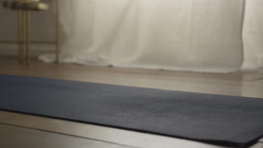A woman does yoga on a yoga mat indoors