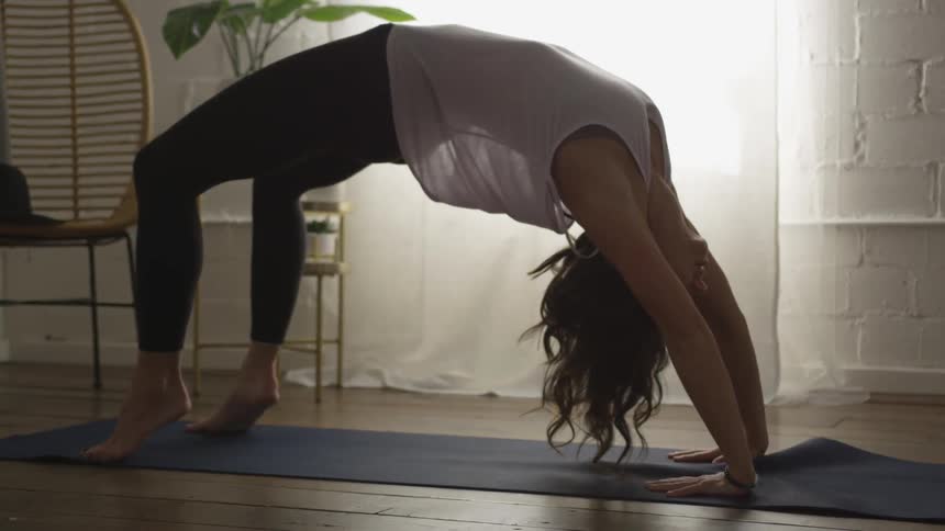 A woman rises up to form a backbend on a yoga mat