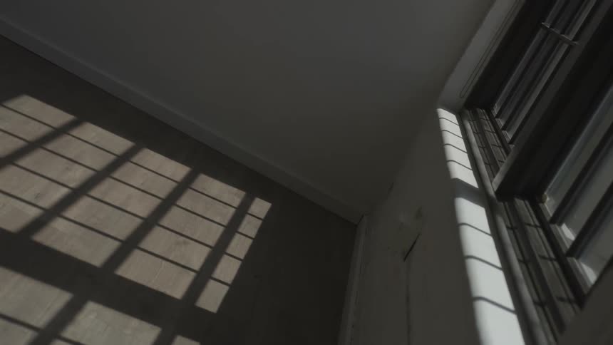 Sunlight through a window casts a shadow on the wall