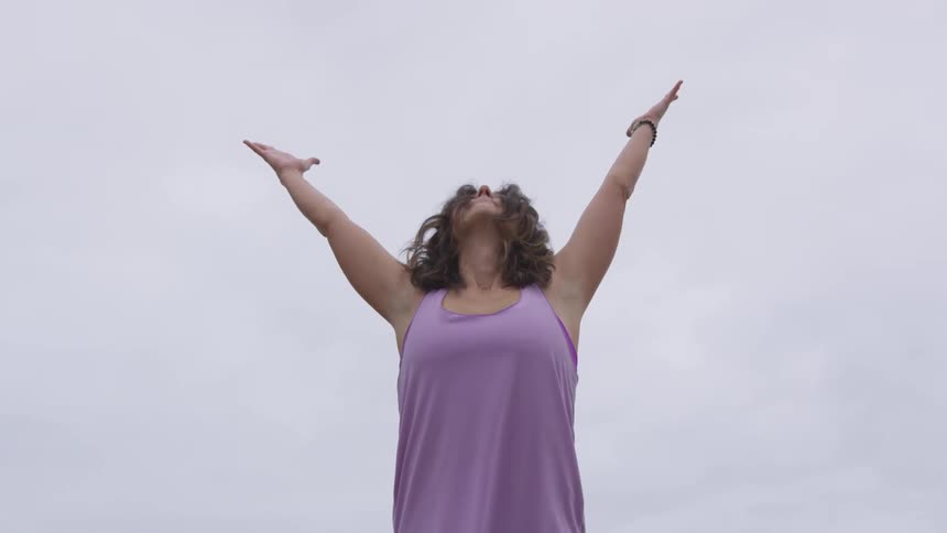 A woman stretches and does yoga outside on a cloudy day