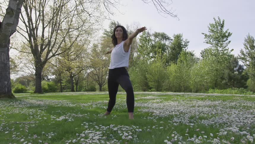 A woman does yoga outside in a meadow