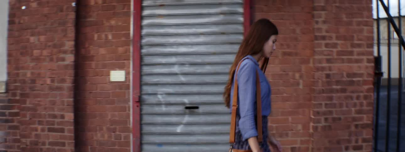 Woman with long brown hair walking down a street
