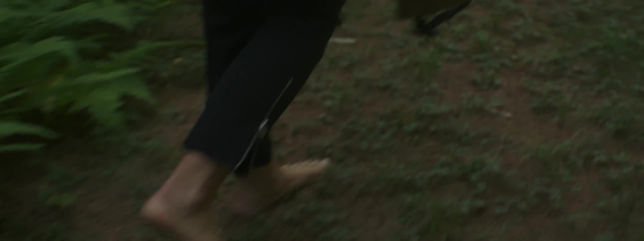 A woman walks barefoot on a forest path