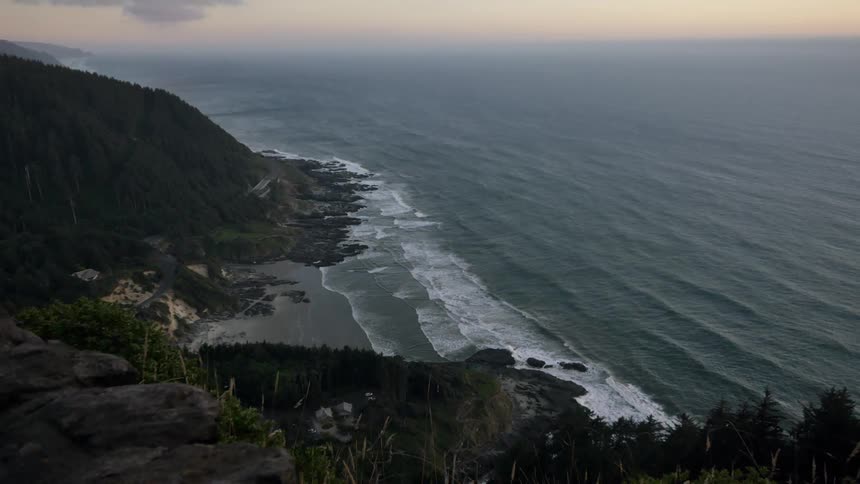 A cliff edge overlooks the beach and ocean cove below