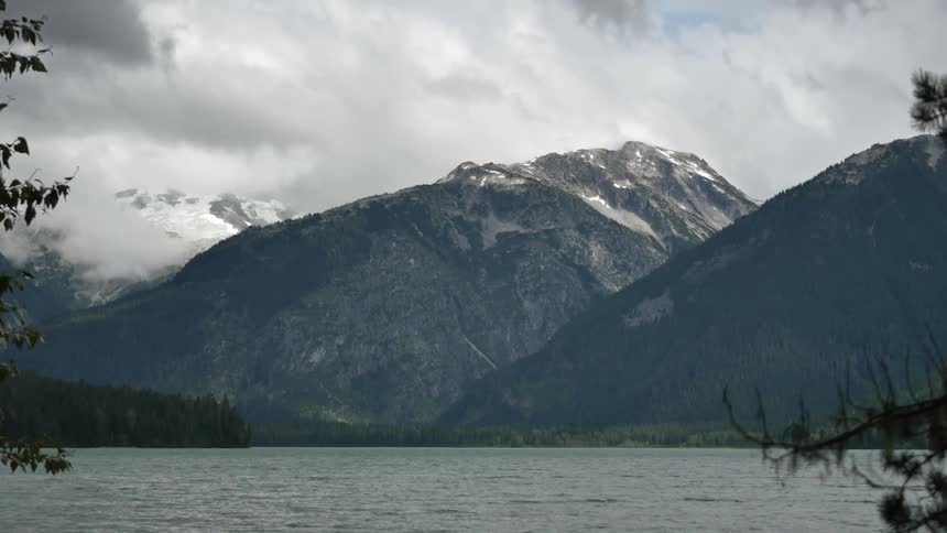 View of snow-capped mountains across a body of water on a cloudy day