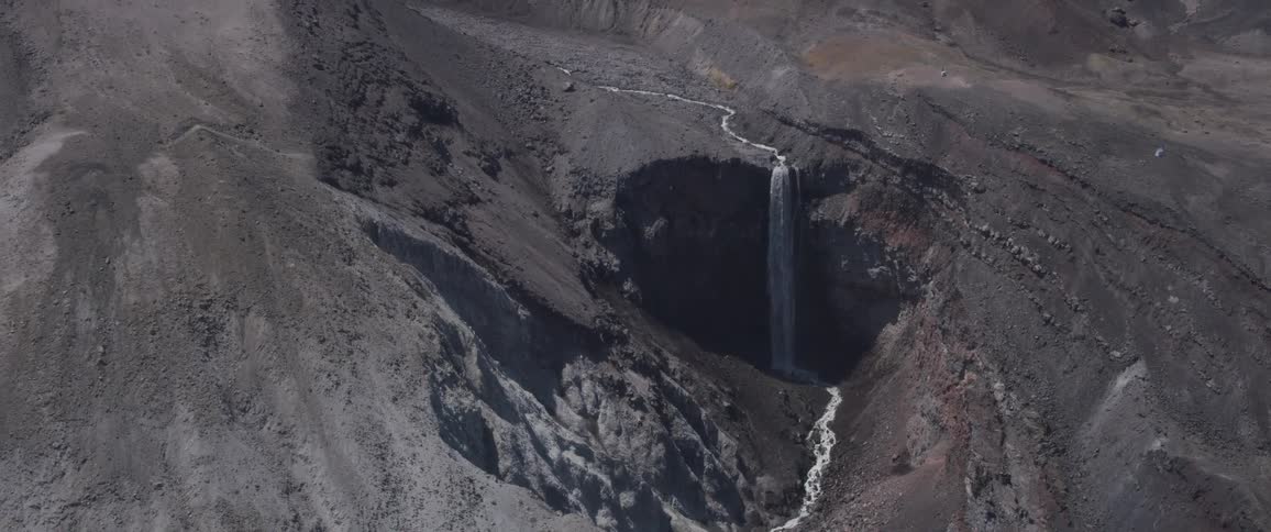 Aerial view of a small waterfall on a barren landscape