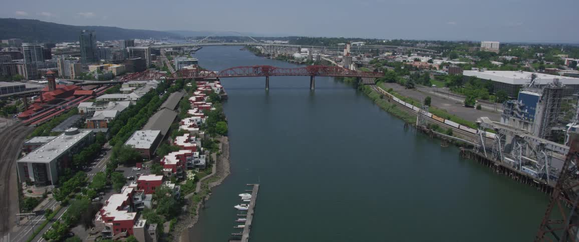 The camera flies over a river surrounded by a city