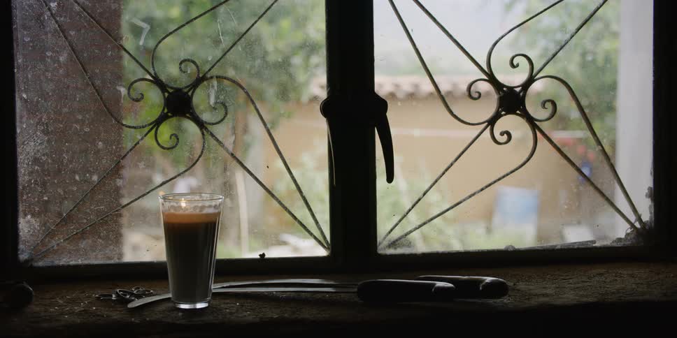 A small candle glass sitting on a windowsill