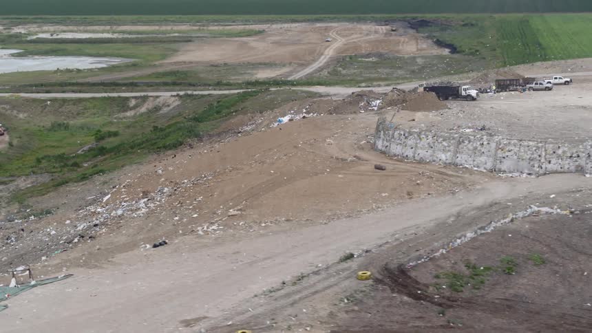 Aerial view of trucks dumping material into an open pit and a bulldozer moving across the pit