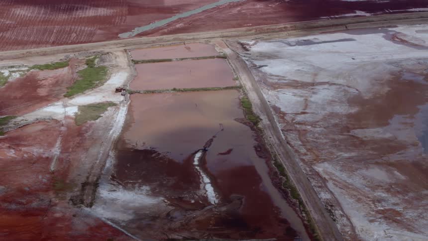 Shadows of clouds moving over deep red chemical waste from a mine