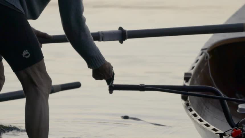 Rain falls into water near man working with boat