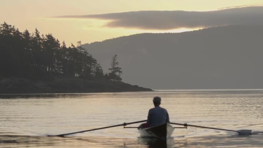 A man on a rowboat on a lake with dark clouds