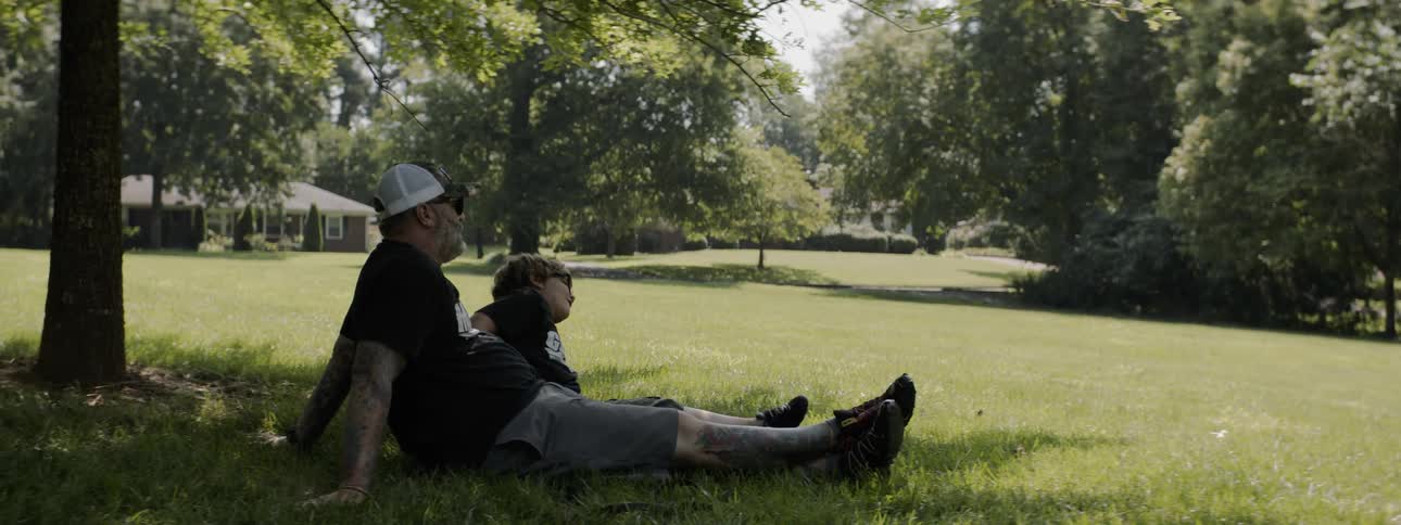 Man and child sit on the grass on a sunny day