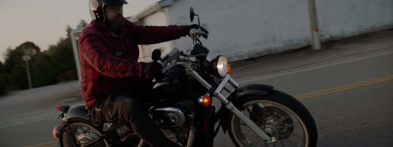 Two bikers pulling into a parking lot in the evening