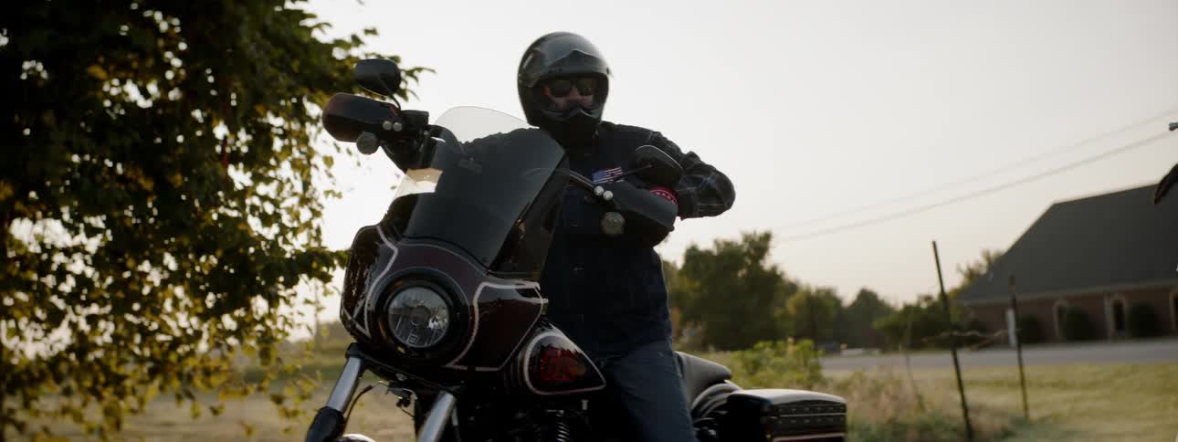 A man in a helmet mounts a motorcycle