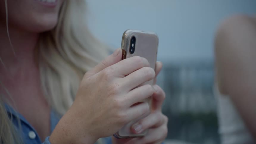 A woman smiles looking at her cell phone