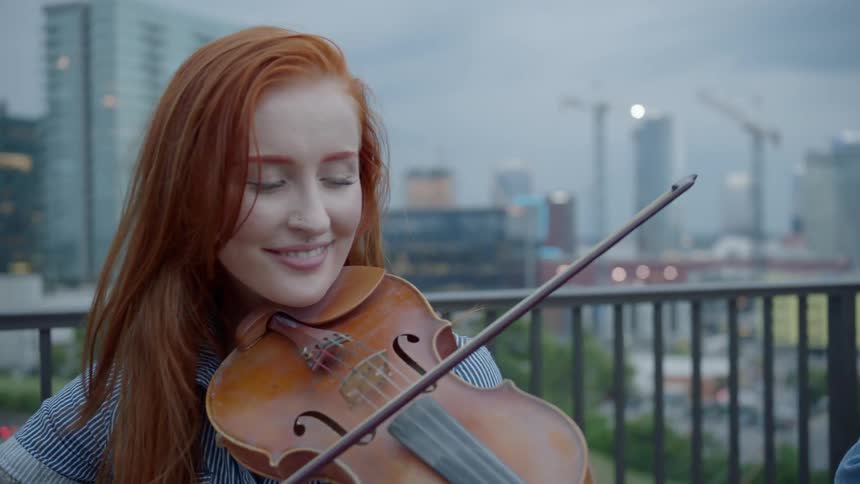 A woman is playing an instrument outdoors