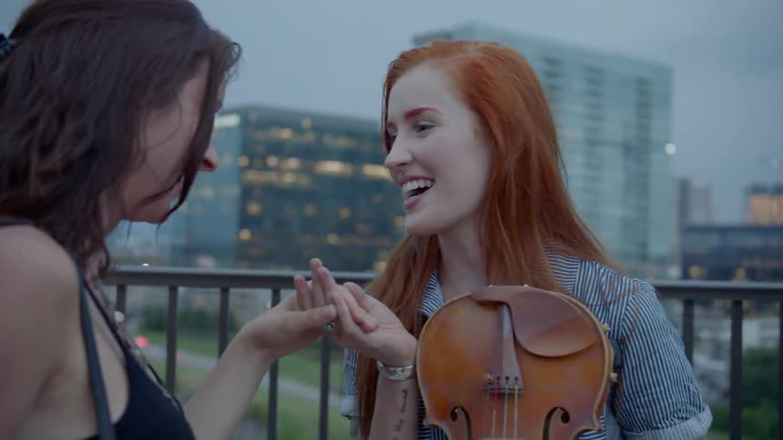 Women talking laughing and holding hands on a bridge at the city