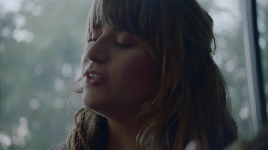A woman sings and plays the guitar