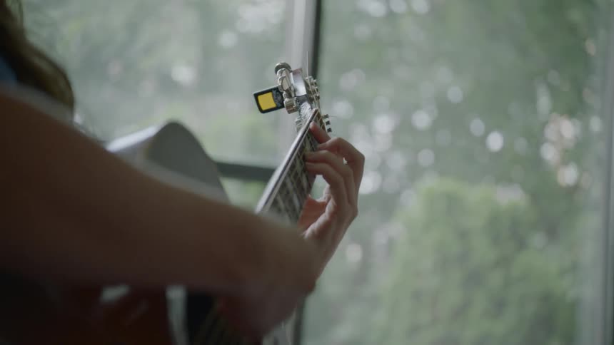 A woman plays guitar in daylight