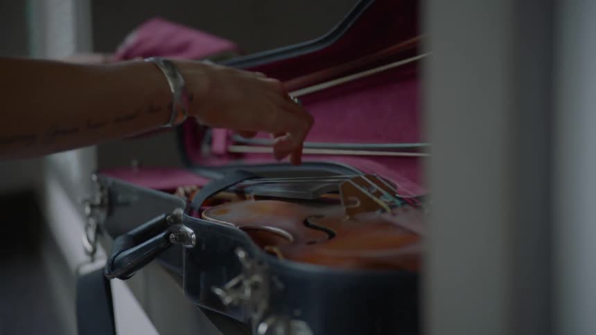 Female hand opening instrument case then taking violin out