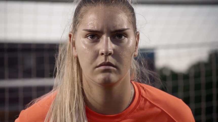 A goalkeeper in a women's soccer match braces herself for shots on goal