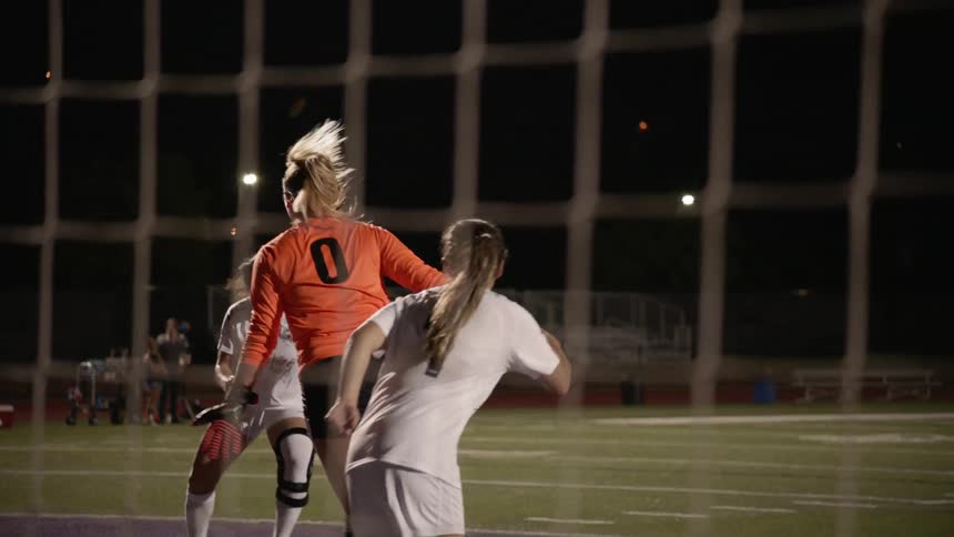 Female goalkeeper tries to catch a ball while other players are trying to score