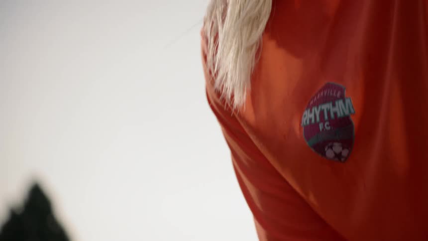 A goalkeeper rubs her hands together and watches the ball