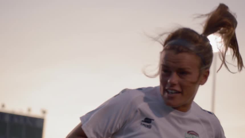 Two women compete for a header in a soccer match