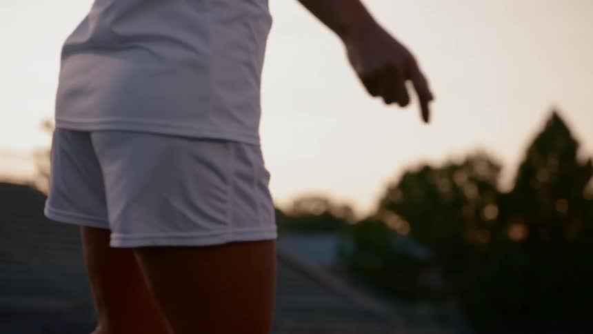A woman soccer plays runs and kicks the ball