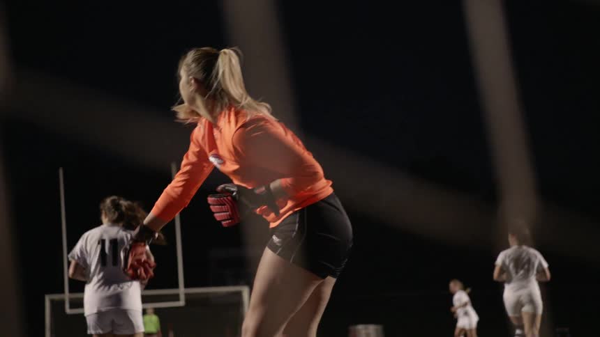 A goalkeeper throws the ball out in a women's soccer match