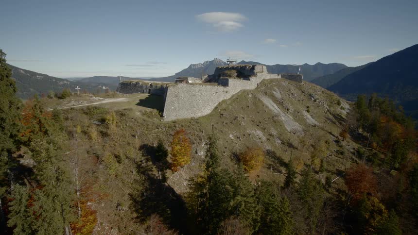 The camera flies over a hillside looking at a building