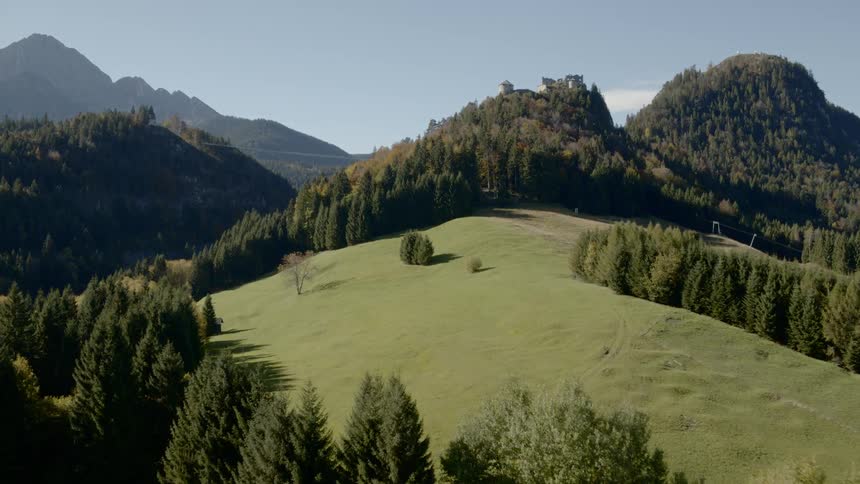 A grassy field surrounded by mountains and forests