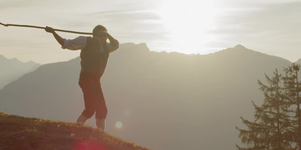 A man swings a large whip through the rural mountain air