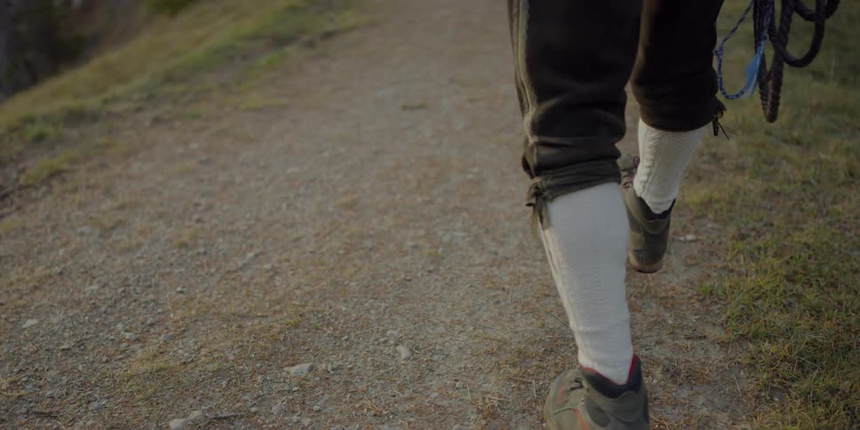 A man carrying rope and wearing riding pants and boots