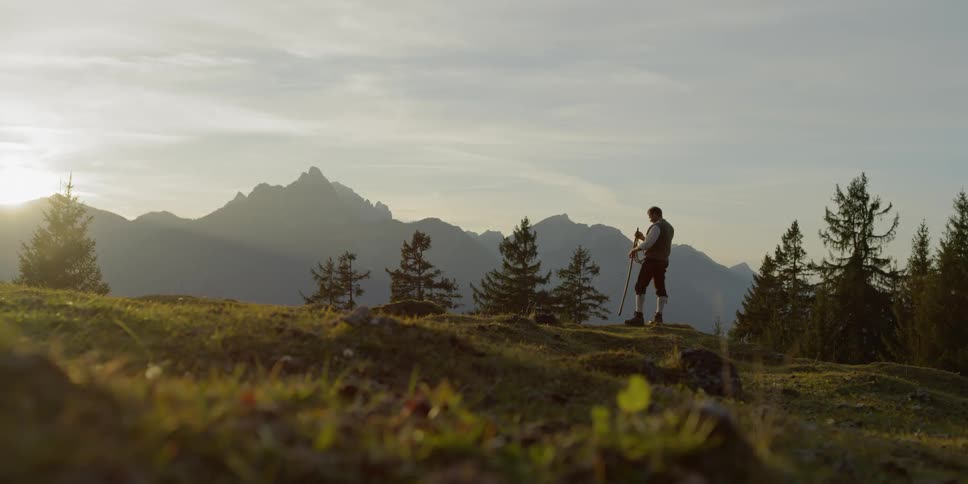 A man stands on a hill with a whip