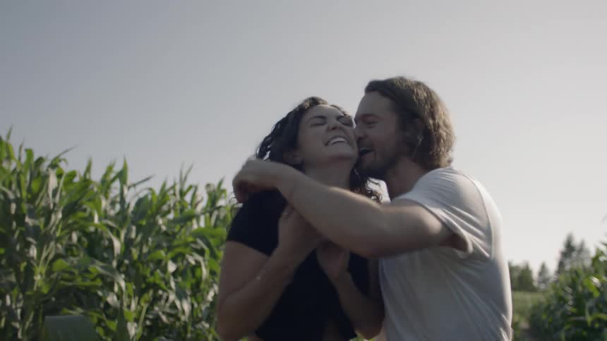 Couple holding hands hugging and having fun while walking through a cornfield
